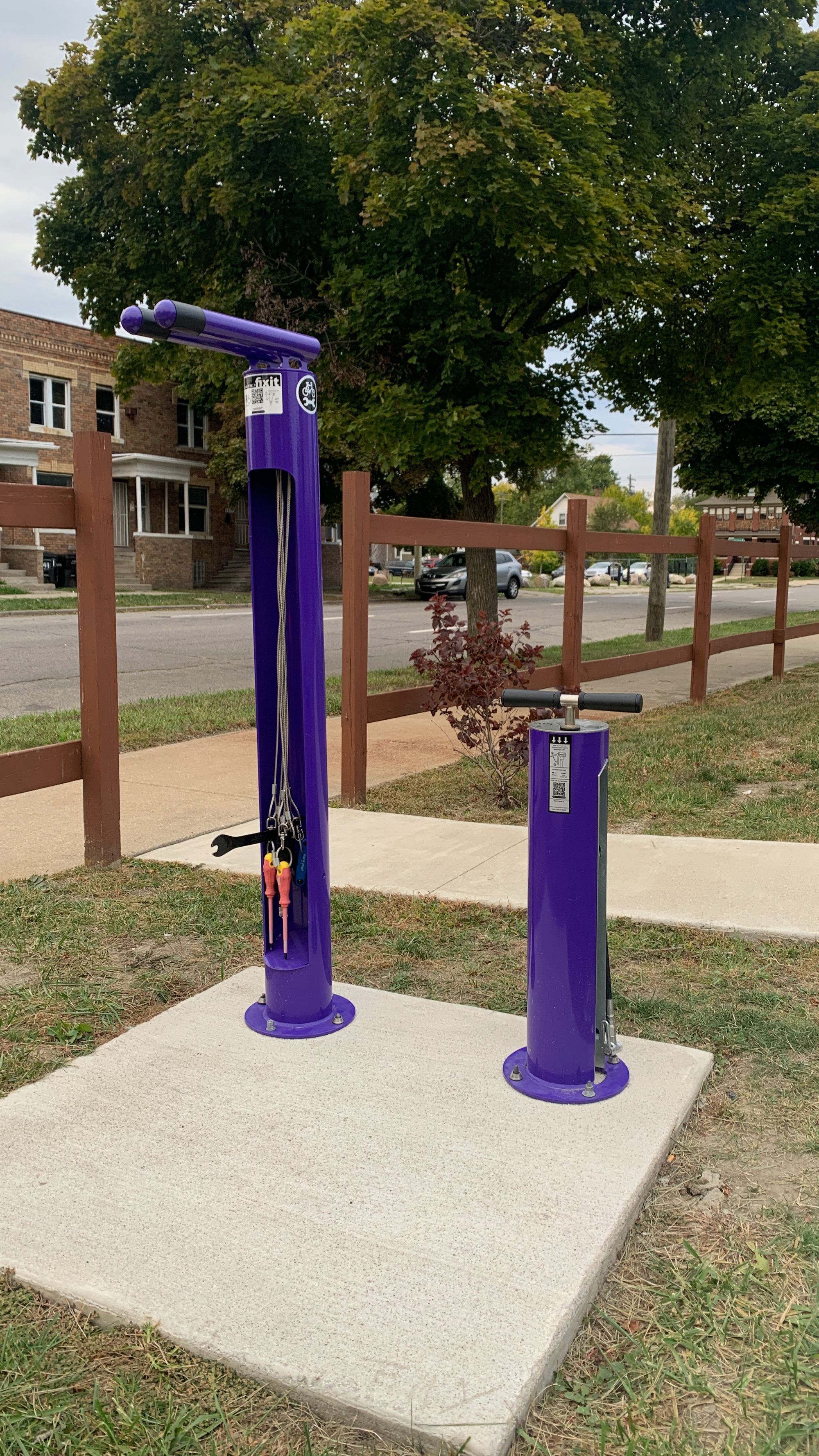 A purple public bike fixit station and pump in a neighborhood.