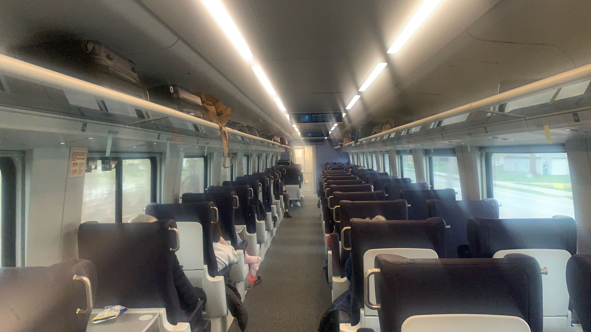 A photo taken from the rear looking down the aisle toward the front of a new Siemens Venture train car. Each row has two seats on the right and a single seat on the left.