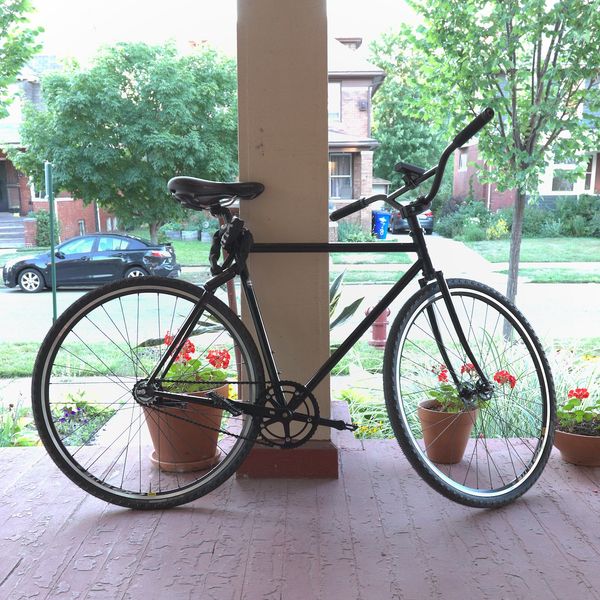 A black fixed wheel bicycle resting on a front porch